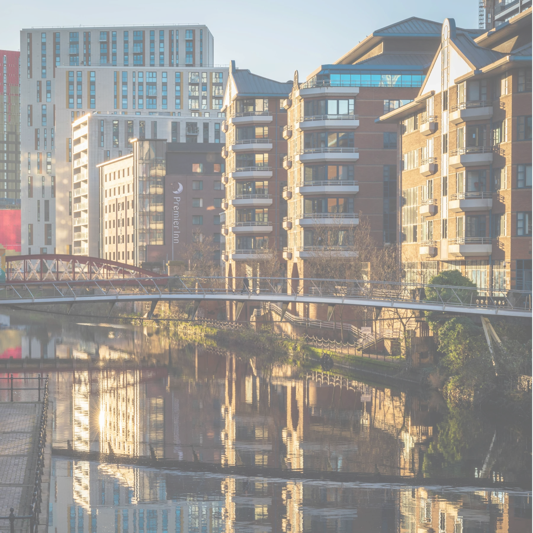 Manchester apartment buildings reflected in the still water of a canal.